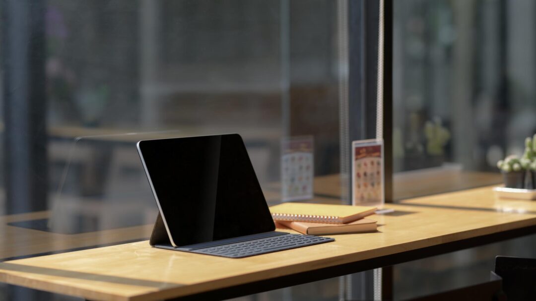 Cropped shot of digital tablet and notebook on wooden desk